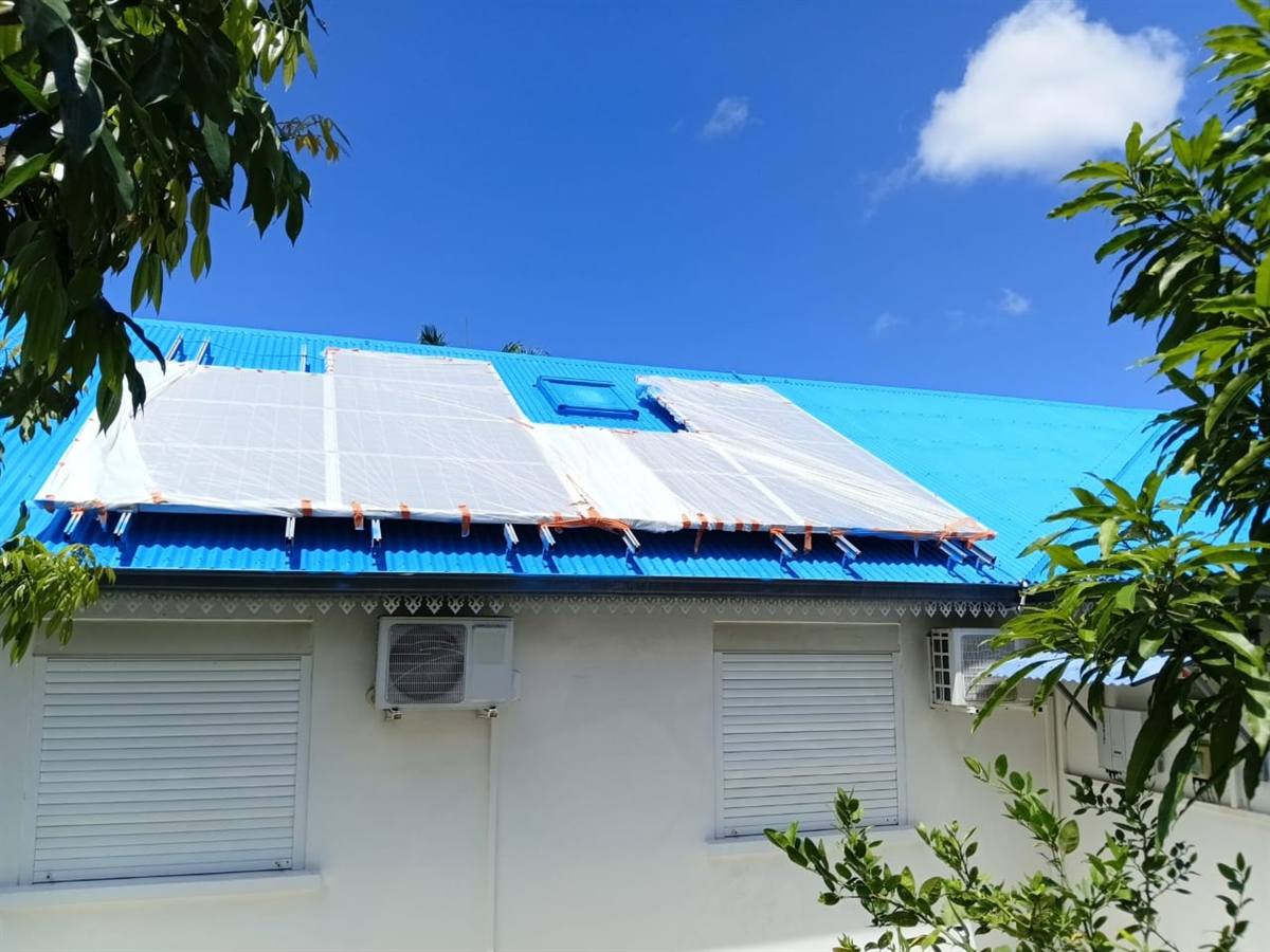Toiture en tôle repeinte en bleu autour de panneaux solaires